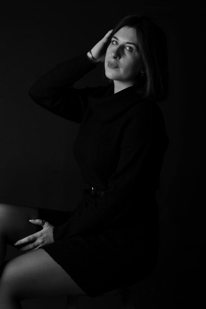 Une femme vêtue d'une robe noire et se tenant les cheveux pose pour une photographe